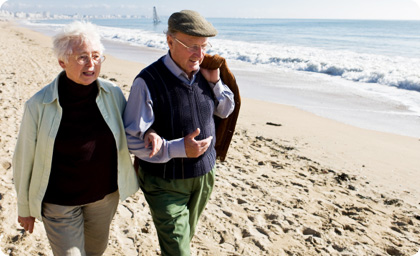 Image of an elderly couple walking on the beach